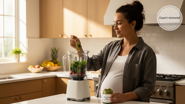 Pregnant woman pouring sea moss gel into a smoothie in a bright kitchen — healthy prenatal nutrition.